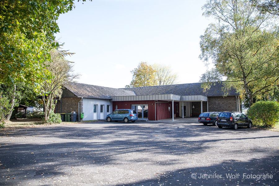 Das Gebäude der Kita Kleine Strolche in Süchterscheid mit Bäumen und Parkplatz
