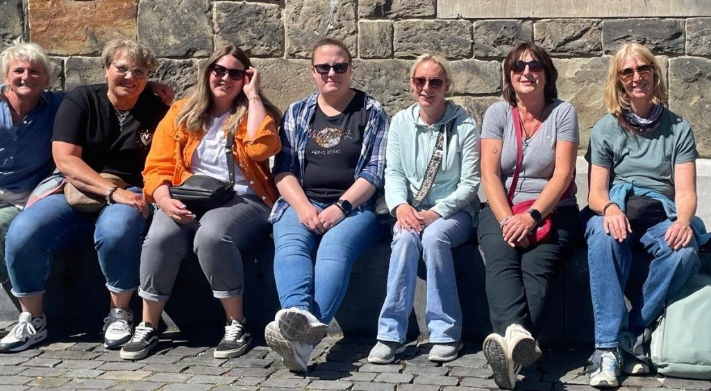 Das Team der Kleinen Strolche sitzt gemeinsam auf einer Steinmauer in der Sonne